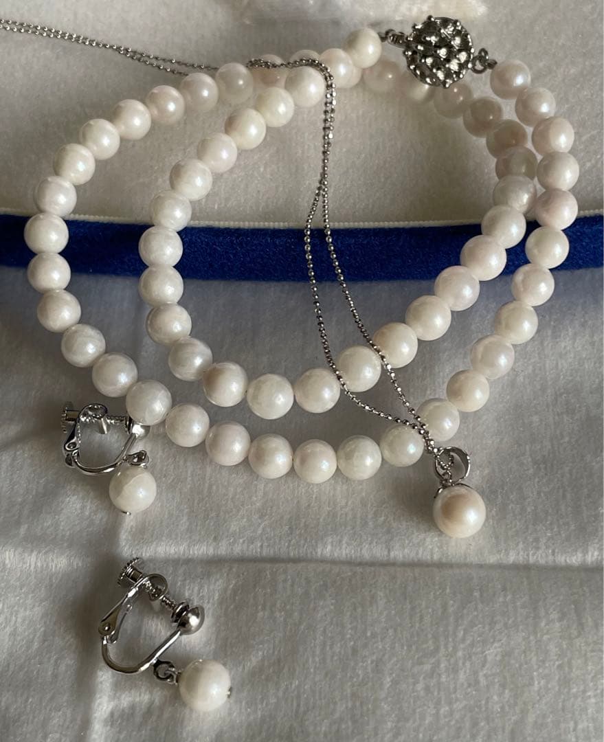 Akoya pearl necklace, earrings, and pendant set with 7mm pearls and silver clasp on white background