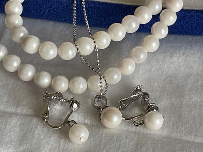 Akoya pearl necklace, earrings, and pendant set with 7mm pearls and silver clasp on white background