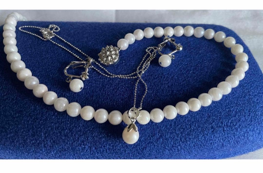 Akoya pearl necklace, earrings, and pendant set with 7mm pearls and silver clasp on white background