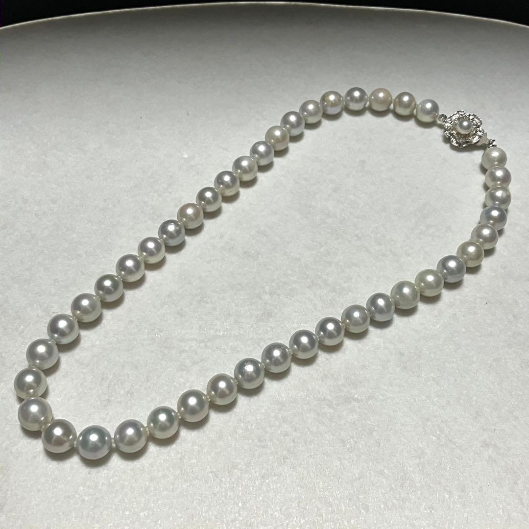 Akoya pearl necklace with 9.5mm blue gray pearls and silver flower clasp on white background