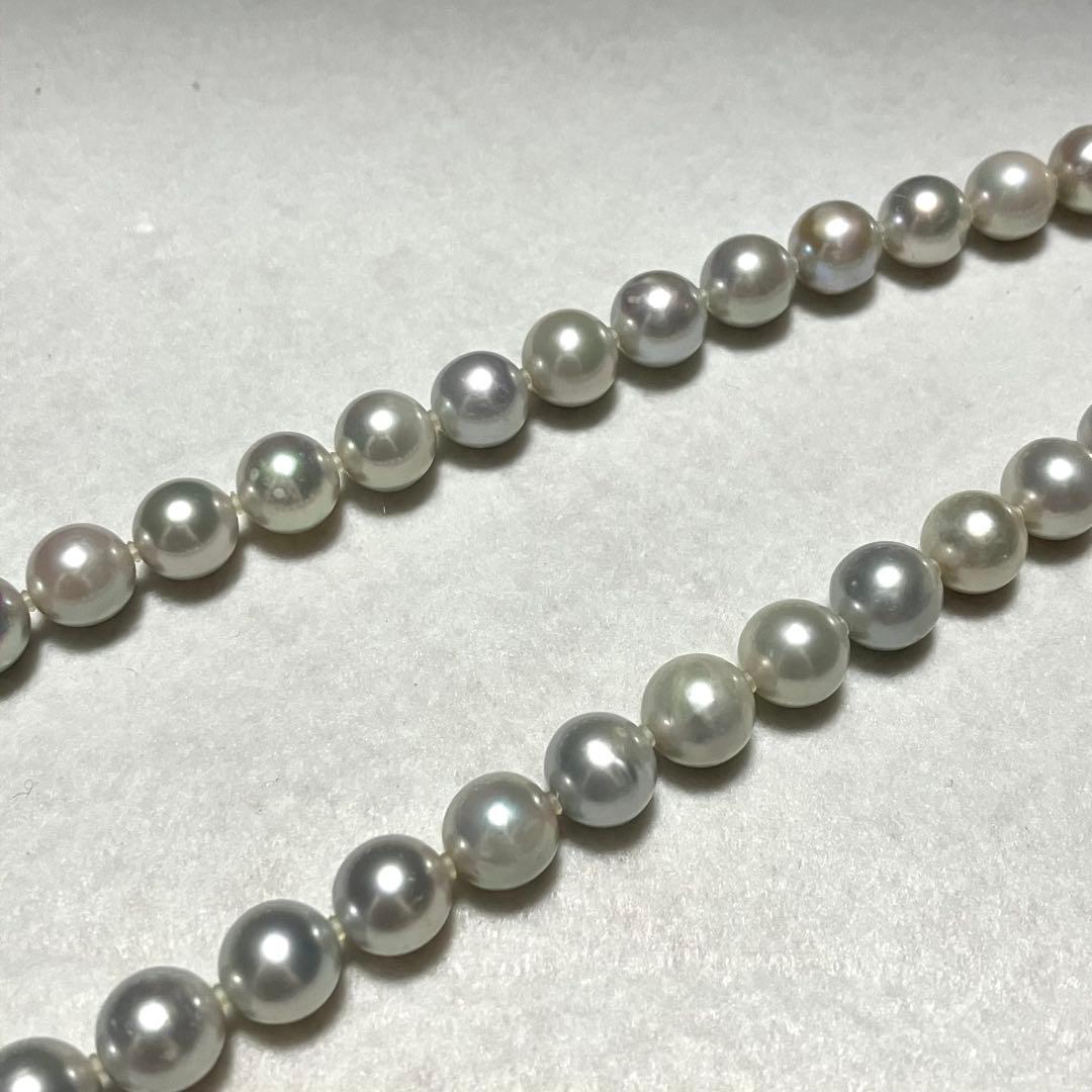 Akoya pearl necklace with 9.5mm blue gray pearls and silver flower clasp on white background