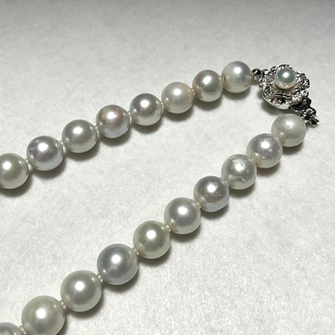 Akoya pearl necklace with 9.5mm blue gray pearls and silver flower clasp on white background