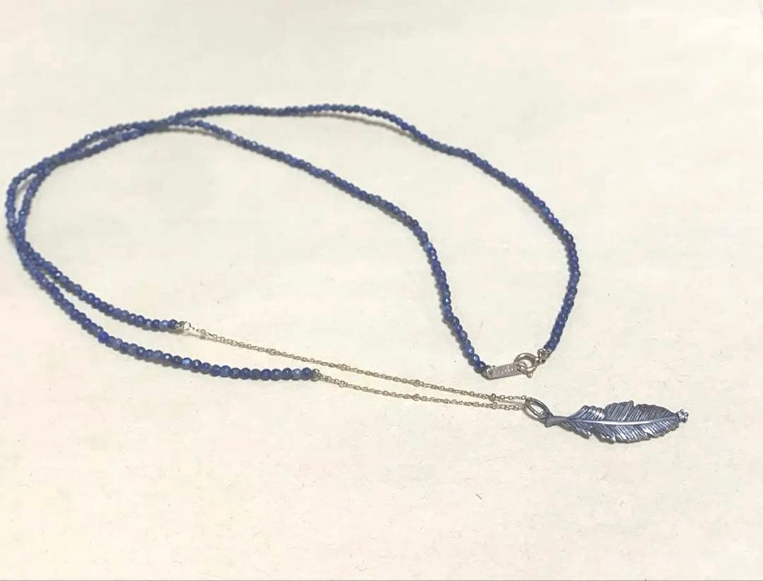 Agete necklace featuring navy lapis lazuli stone with 10 karat gold chain and silver feather charm set