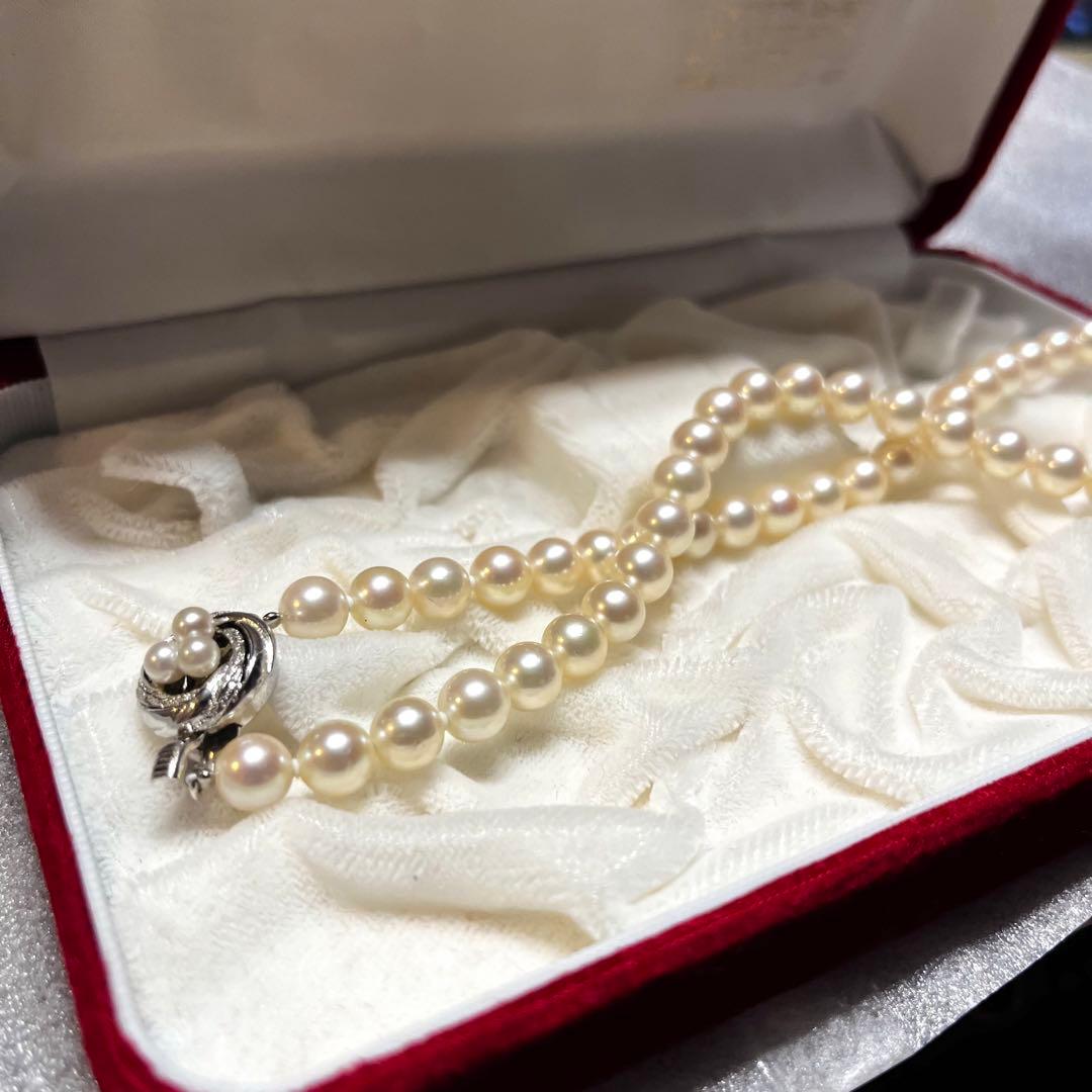 Akoya pearl necklace with 7mm pearls, silver clasp, 43cm length, and three baby pearls on a white background