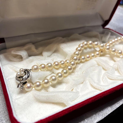 Akoya pearl necklace with 7mm pearls, silver clasp, 43cm length, and three baby pearls on a white background