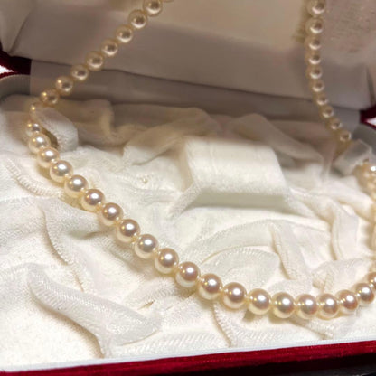 Akoya pearl necklace with 7mm pearls, silver clasp, 43cm length, and three baby pearls on a white background