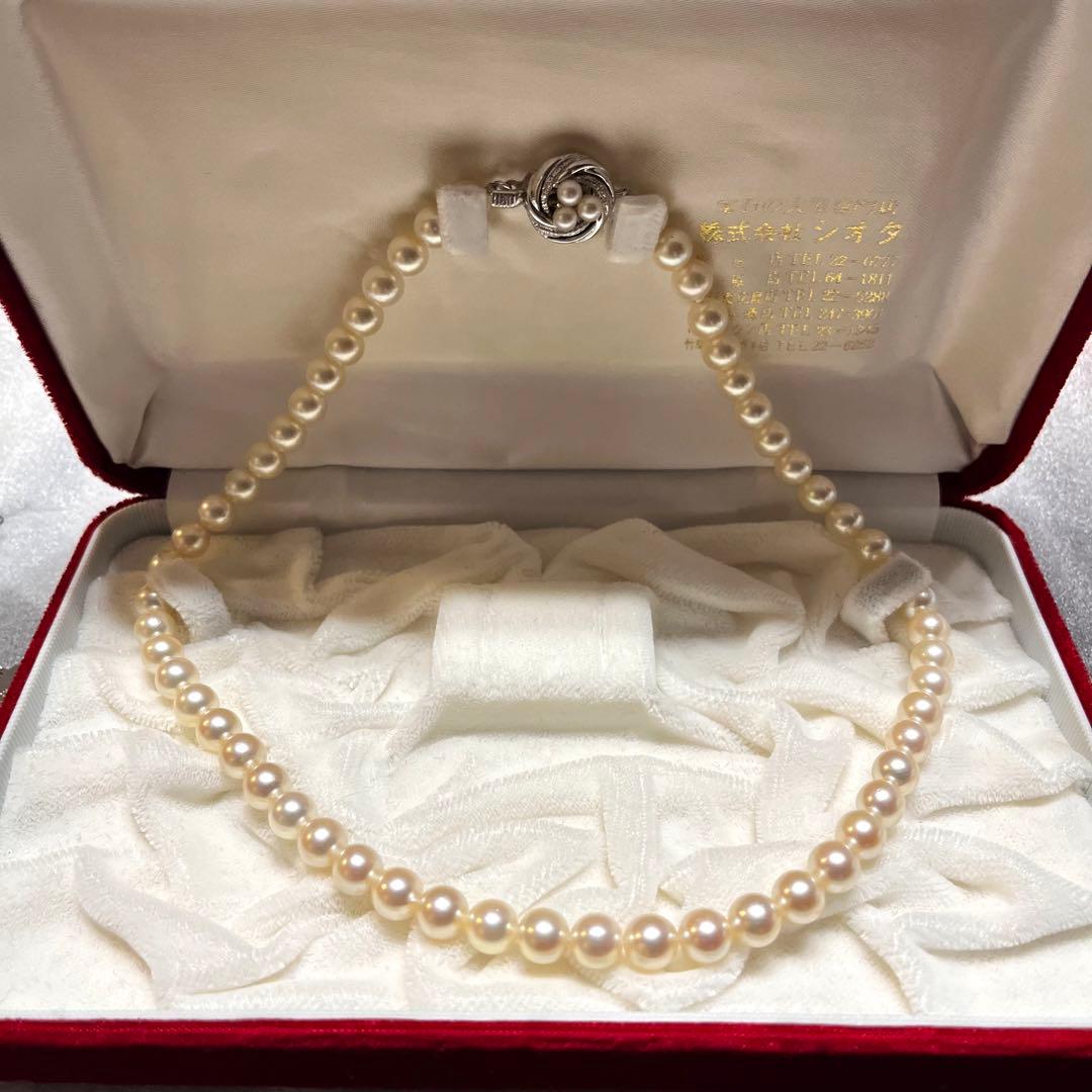 Akoya pearl necklace with 7mm pearls, silver clasp, 43cm length, and three baby pearls on a white background