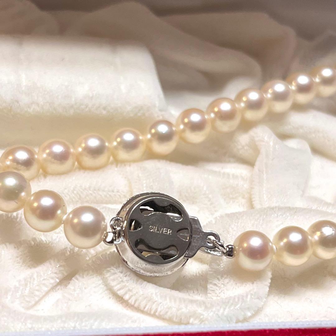 Akoya pearl necklace with 7mm pearls, silver clasp, 43cm length, and three baby pearls on a white background