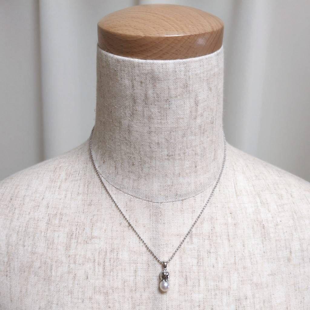 Tasaki silver necklace with 7.5mm pearl and matching brooch on white background