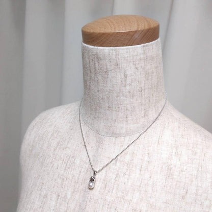 Tasaki silver necklace with 7.5mm pearl and matching brooch on white background