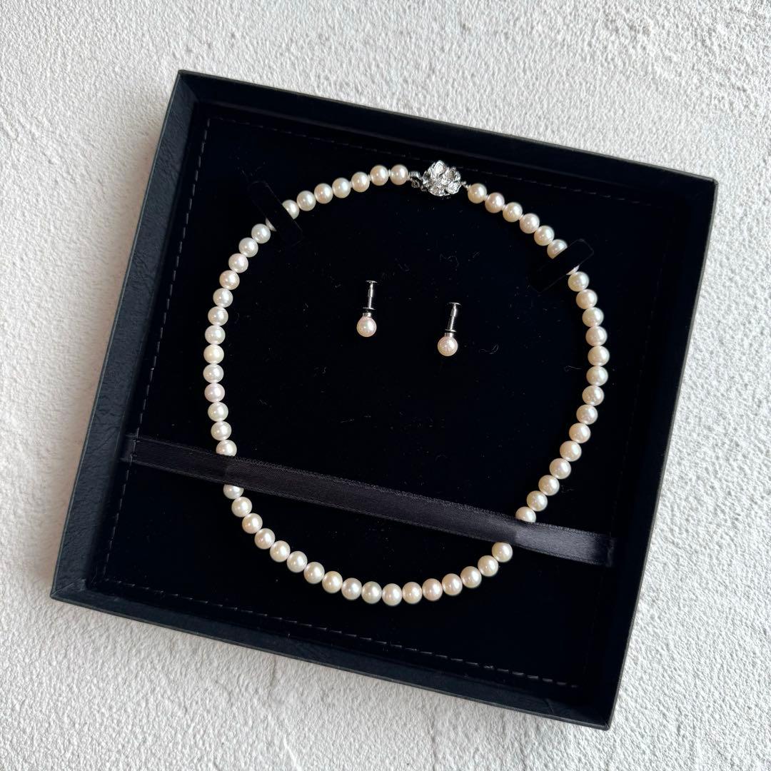 Akoya pearl necklace and earring set with white pearls and silver fittings displayed with black box