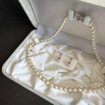 Akoya pearl necklace and earring set with white pearls and silver fittings displayed with black box