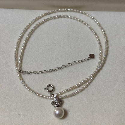 Pearl and silver double necklace with crown motif pendant and lobster clasp on white background