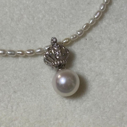Pearl and silver double necklace with crown motif pendant and lobster clasp on white background