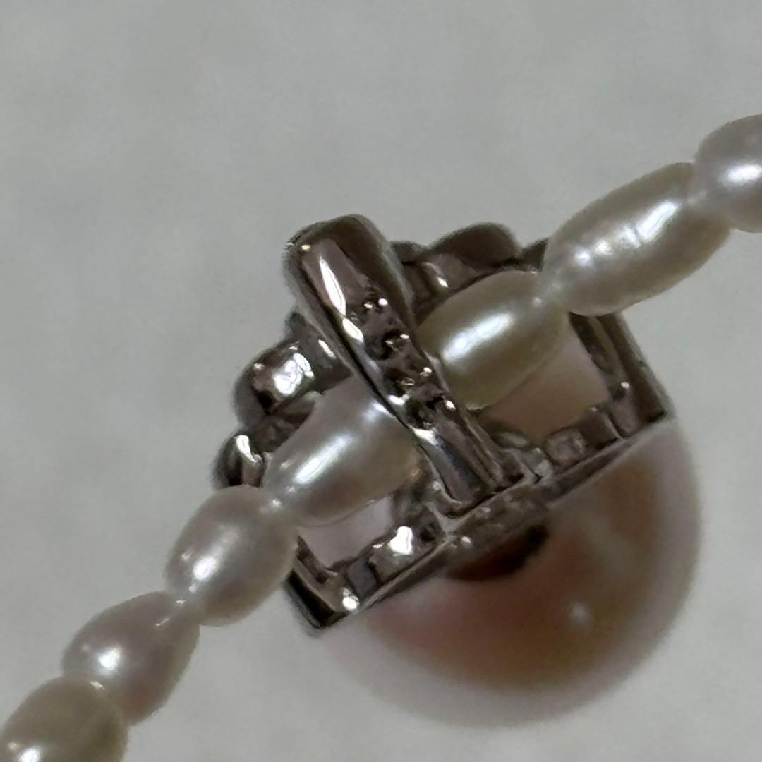 Pearl and silver double necklace with crown motif pendant and lobster clasp on white background