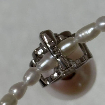 Pearl and silver double necklace with crown motif pendant and lobster clasp on white background