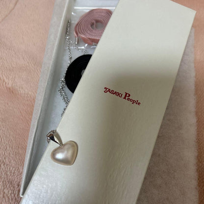 Tasaki Pearl Heart Necklace with pearl pendant and pink and black velvet ribbon set on white background
