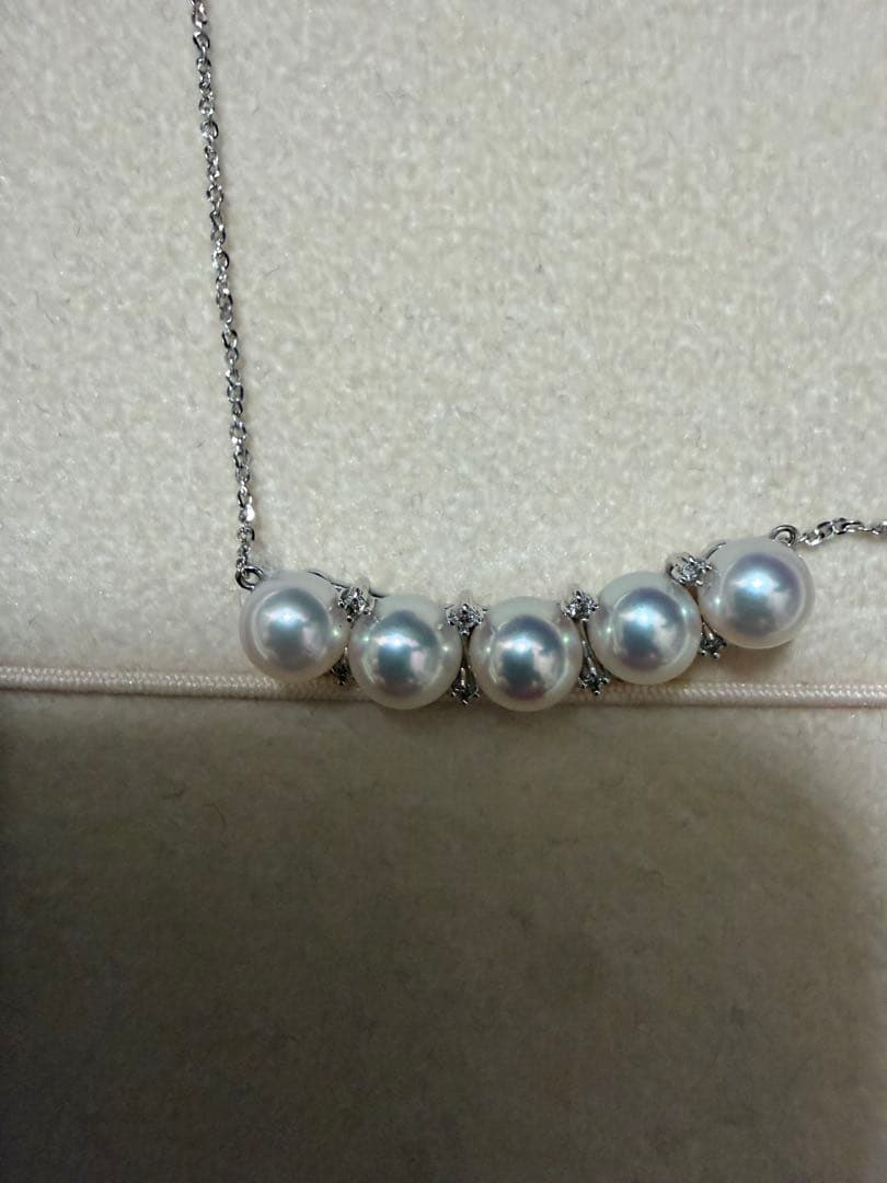 Pearl necklace adorned with sparkling diamonds displayed on a white background