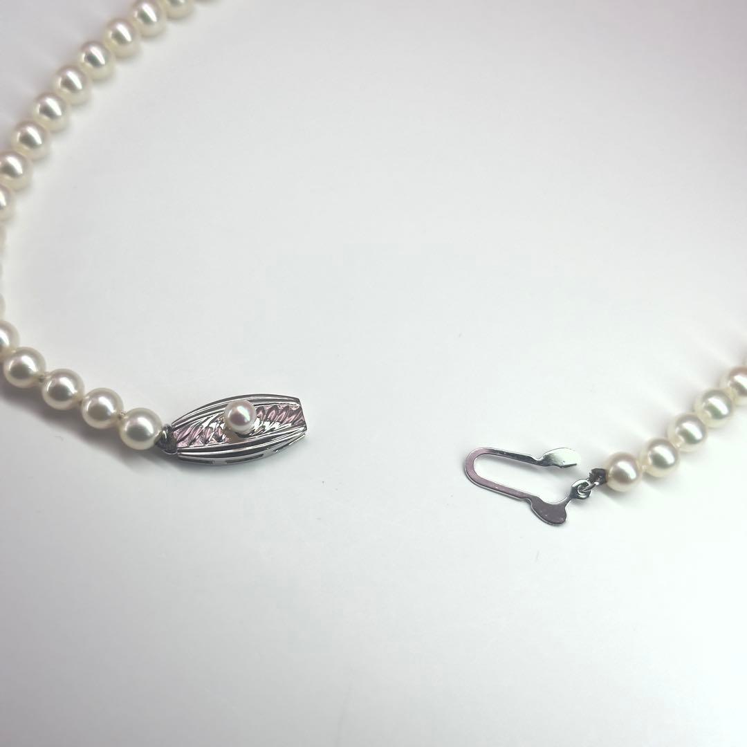 MIKIMOTO pearl necklace made of silver with round white pearls on a white background