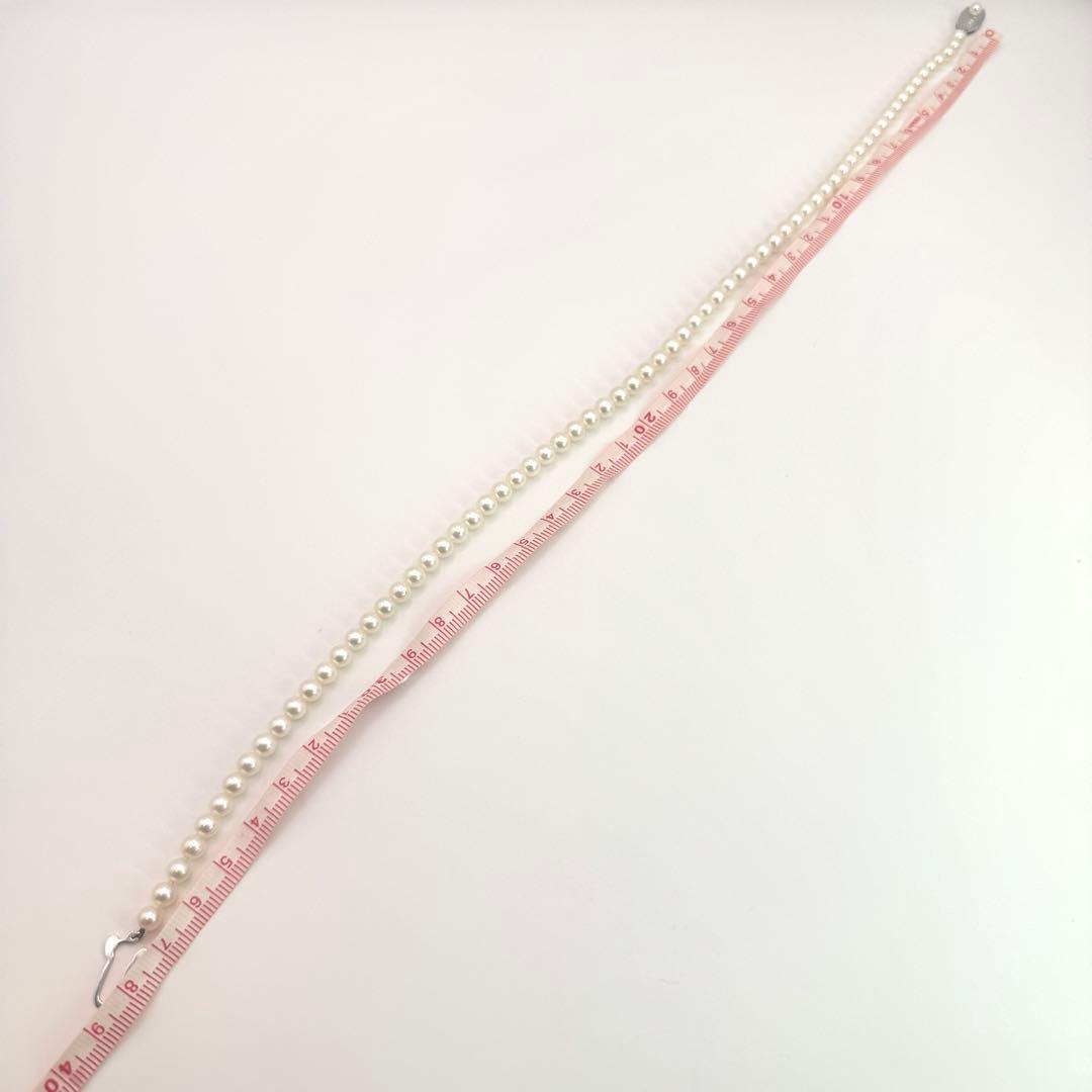 MIKIMOTO pearl necklace made of silver with round white pearls on a white background