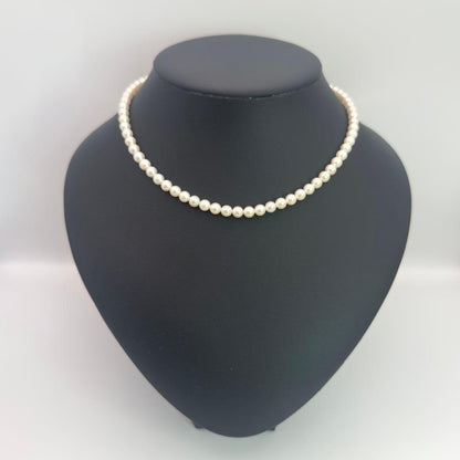 MIKIMOTO pearl necklace made of silver with round white pearls on a white background