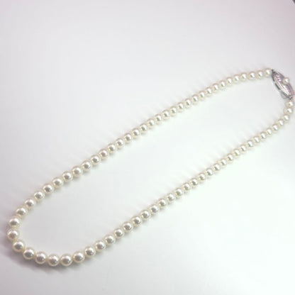 MIKIMOTO pearl necklace made of silver with round white pearls on a white background