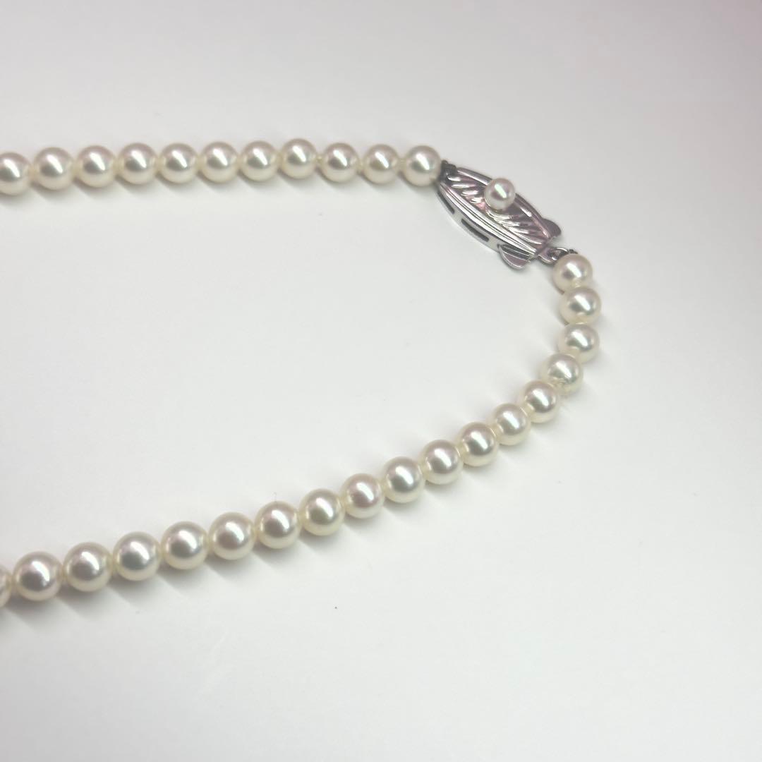 MIKIMOTO pearl necklace made of silver with round white pearls on a white background