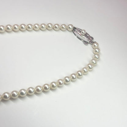 MIKIMOTO pearl necklace made of silver with round white pearls on a white background