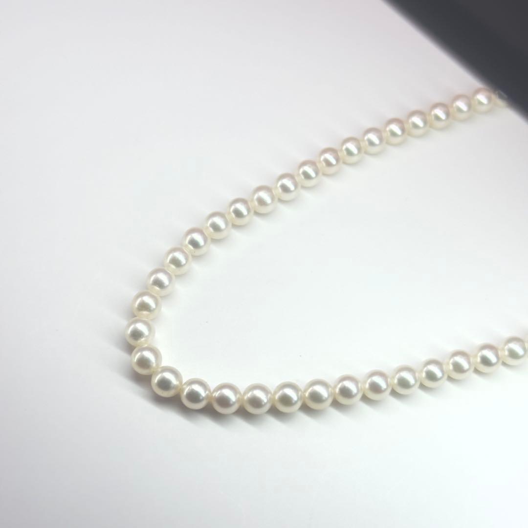 MIKIMOTO pearl necklace made of silver with round white pearls on a white background