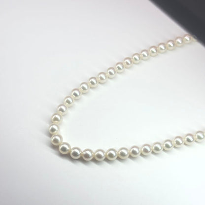 MIKIMOTO pearl necklace made of silver with round white pearls on a white background