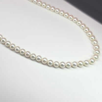 MIKIMOTO pearl necklace made of silver with round white pearls on a white background