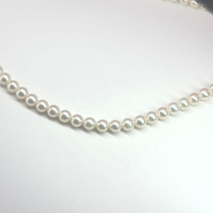 MIKIMOTO pearl necklace made of silver with round white pearls on a white background