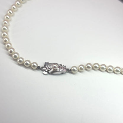 MIKIMOTO pearl necklace made of silver with round white pearls on a white background