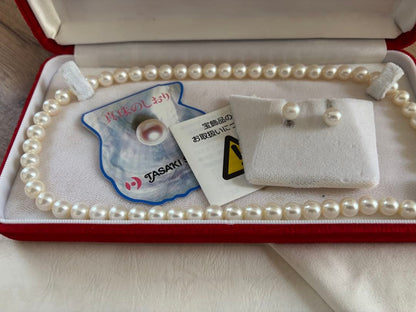 Tasaki pearl necklace and matching earrings set displayed on a white background