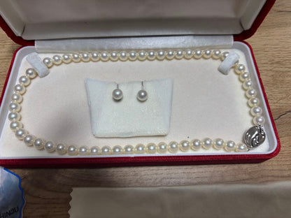 Tasaki pearl necklace and matching earrings set displayed on a white background