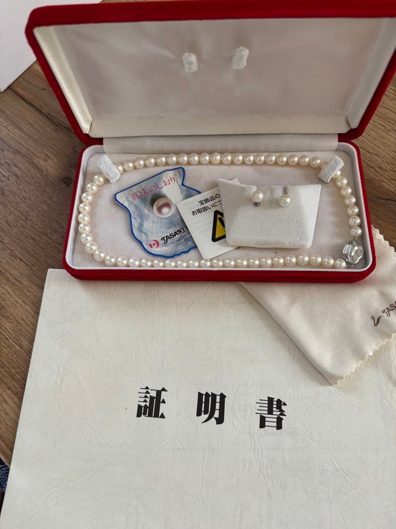 Tasaki pearl necklace and matching earrings set displayed on a white background