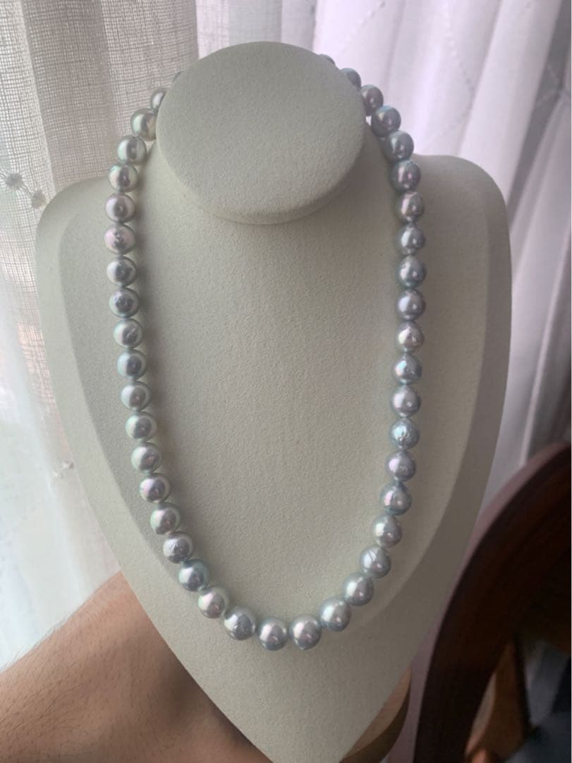 Akoya pearl necklace with natural blue pearls sized 9 to 10 millimeters arranged on a white background