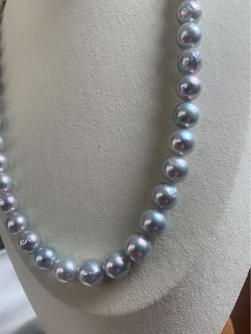 Akoya pearl necklace with natural blue pearls sized 9 to 10 millimeters arranged on a white background
