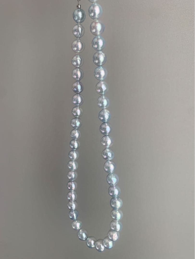 Akoya pearl necklace with natural blue pearls sized 9 to 10 millimeters arranged on a white background