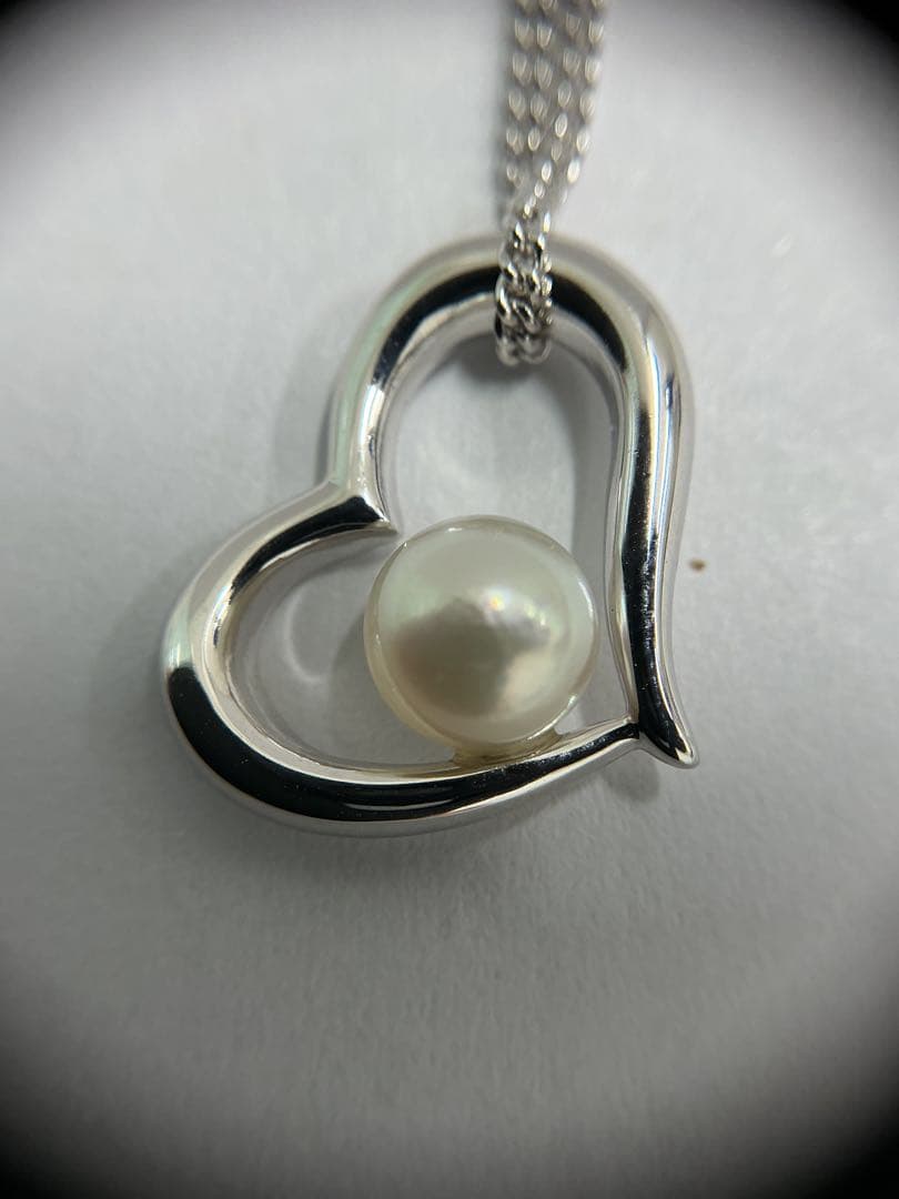 Silver color necklace featuring a heart motif decorated with a pearl and a hook clasp