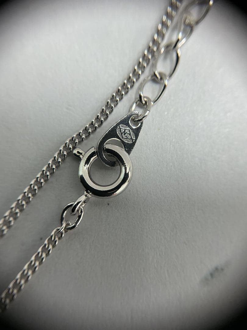 Silver color necklace featuring a heart motif decorated with a pearl and a hook clasp