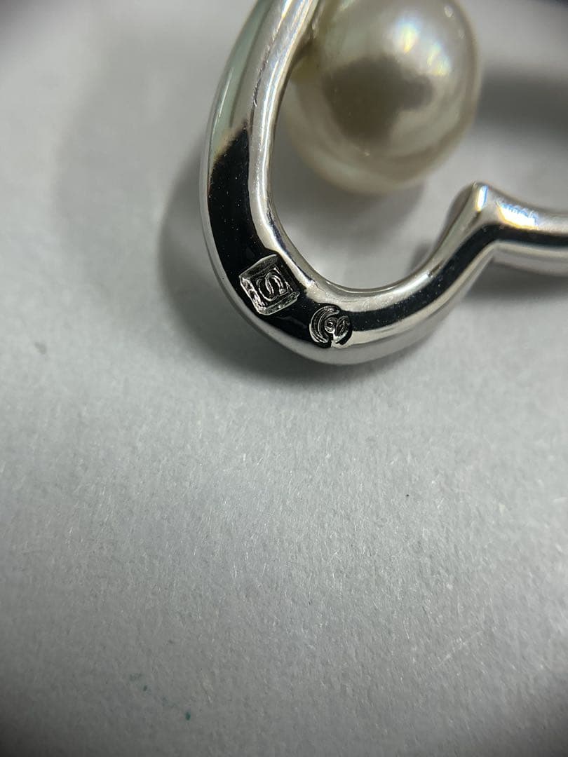 Silver color necklace featuring a heart motif decorated with a pearl and a hook clasp