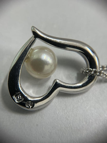 Silver color necklace featuring a heart motif decorated with a pearl and a hook clasp