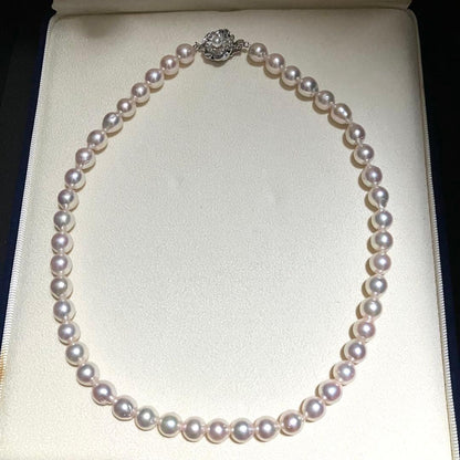 Akoya pearl necklace with white to light pink 8.0mm pearls and silver flower motif clasp on white background