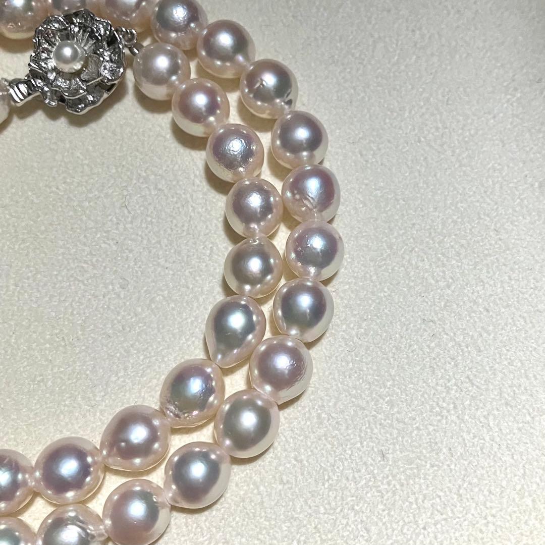 Akoya pearl necklace with white to light pink 8.0mm pearls and silver flower motif clasp on white background
