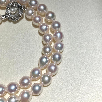 Akoya pearl necklace with white to light pink 8.0mm pearls and silver flower motif clasp on white background