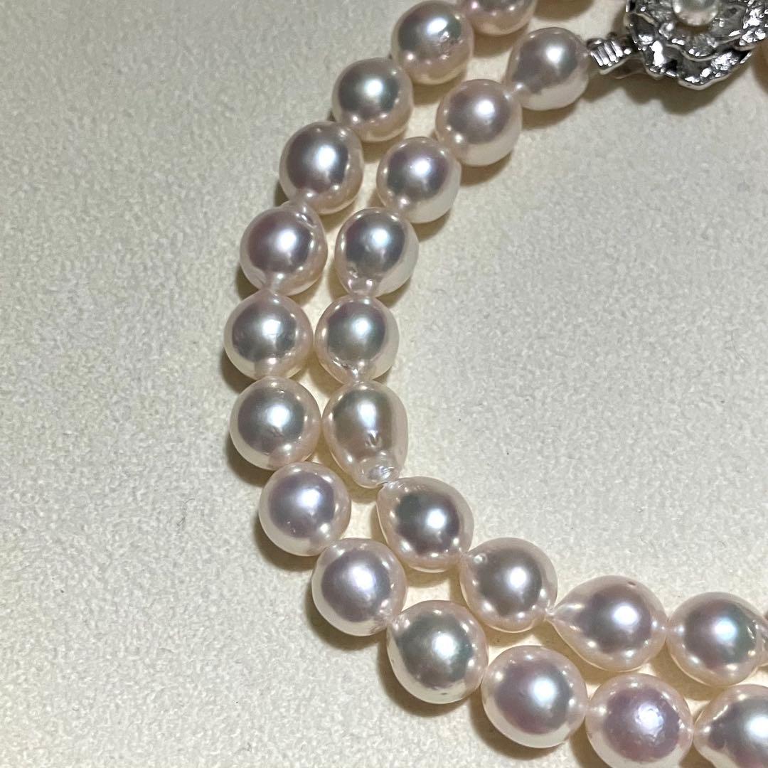 Akoya pearl necklace with white to light pink 8.0mm pearls and silver flower motif clasp on white background