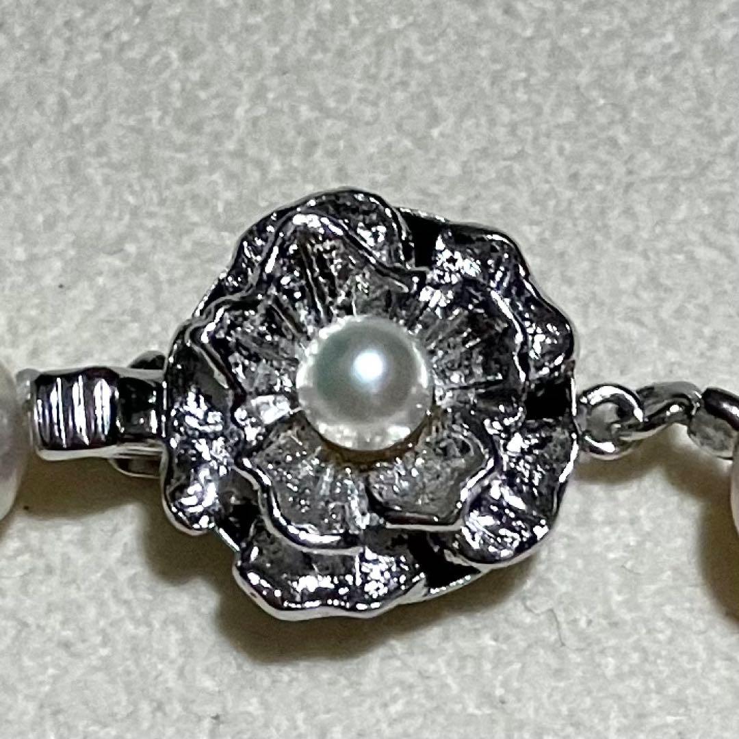 Akoya pearl necklace with white to light pink 8.0mm pearls and silver flower motif clasp on white background