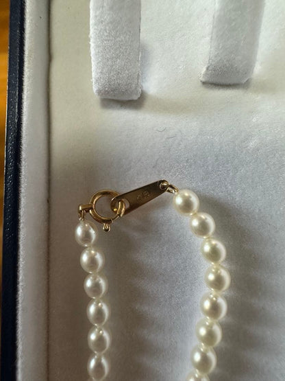 Tasaki K18 gold pearl necklace with small pearls and single larger pearl at end, 42cm length