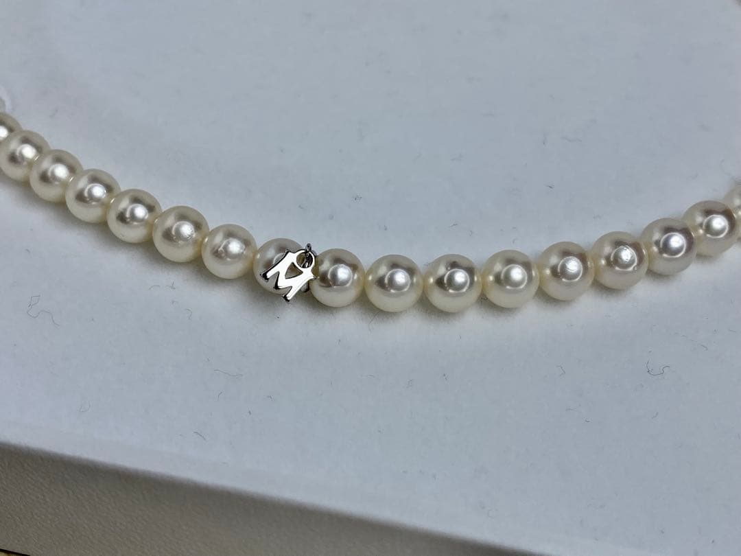 MIKIMOTO K14 Akoya pearl necklace with 6.5-7mm pearls, M charm, and K14WG mark on white background